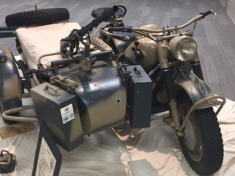 Museum artifact of three wheel vehicle with attached artillery.